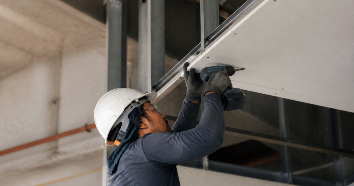 Ouvrier fixant panneaux blancs contre structure metallique suspendue