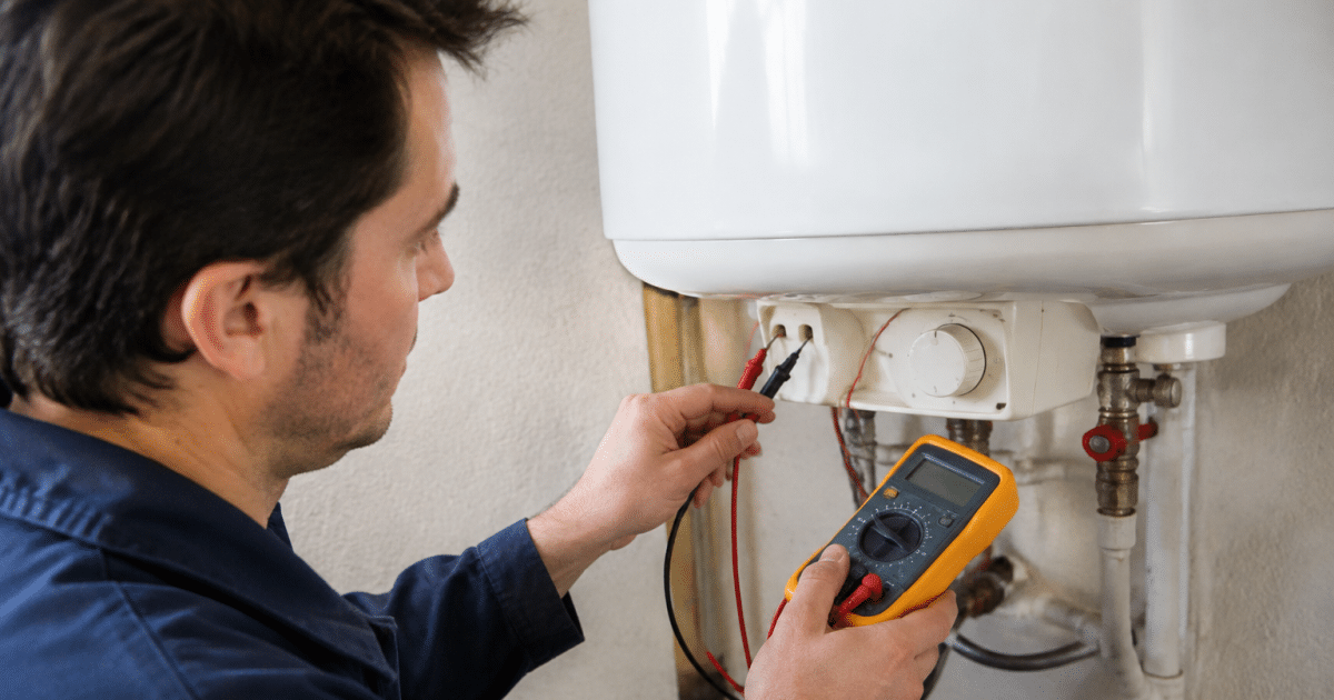 Main tenant un multimetre contre thermostat chauffe-eau blanc