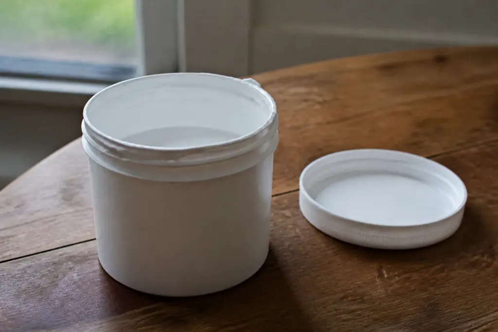 Pot de peinture blanche ouvert sur table en bois